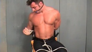 Muscular shirtless officer bound gagged and struggling.