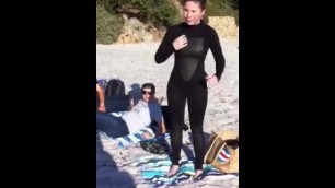 Girl putting on wetsuit at the beach