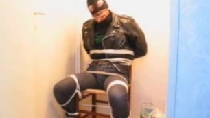 Man tied to chair and gagged wearing leather jacket jeans and cowboy boots