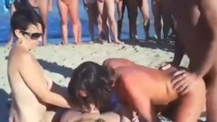 2 Paare haben einen Vierer am Strand während andere zuschauen und wichsen