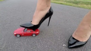 Woman crushing a toy car with black high heels