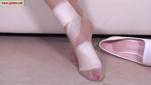 Chinese beauty wraps bandage over her tan hosed foot but not for injury