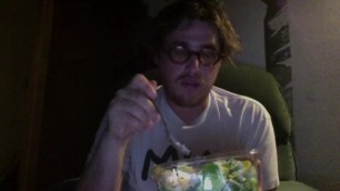 Alternative guy eats HUGE salad while cat watches.